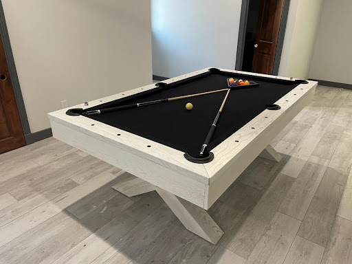 White wooden custom pool table with black felt in the Trooper Billiards showroom.