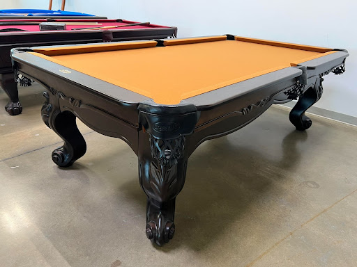 Custom pool table with orange felt and a high-gloss finish in the Trooper Billiards showroom.